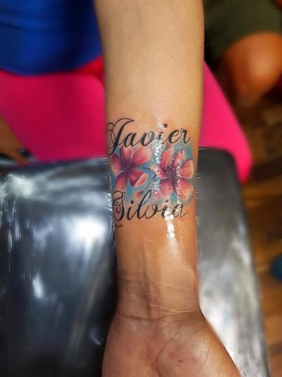 Flores y nombre tatuaje realizado por Baloo Rodríguez