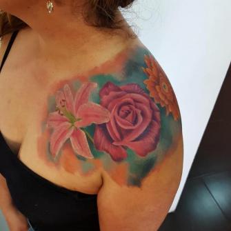 Flores en el hombro tatuaje realizado por Carlos Koyote Ramirez