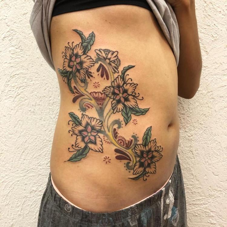 Flores costillas tatuaje realizado por Maferchu Tattoo