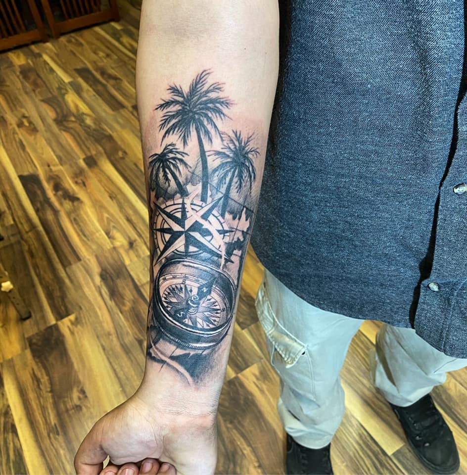 brujula y palmeras  tatuaje realizado por Omar Mendoza 