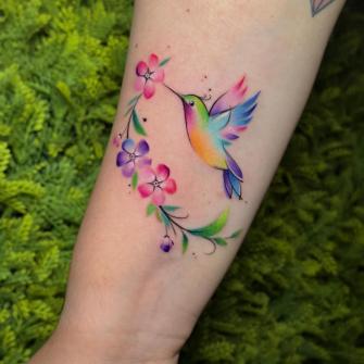 Colibrí con flores tatuaje realizado por Mani Broowns